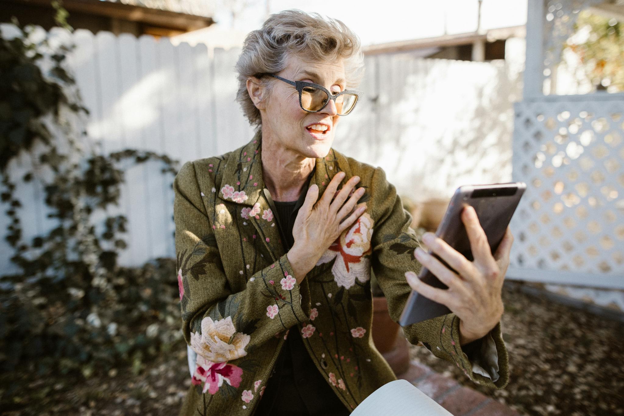 Senior woman engaging in a video call outdoors with a free lifeline smartphone, expressing joy and communication.